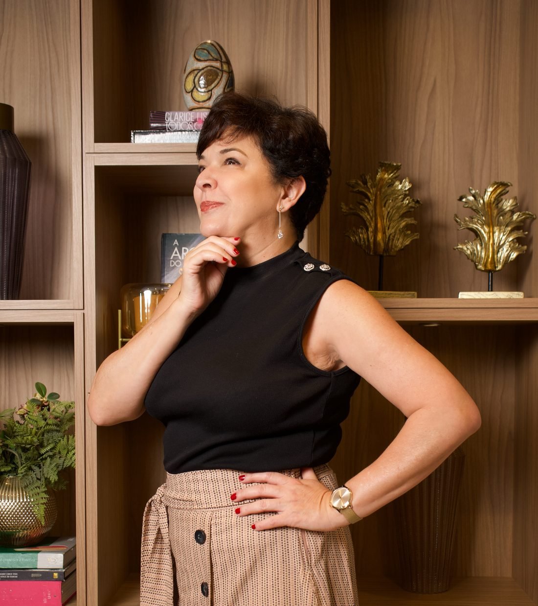 Dra. Silvia Cuartero, com a mão no queixo, diante de uma estante